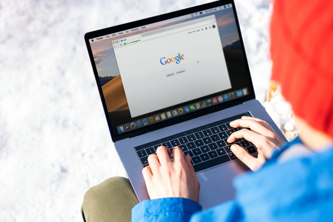 A person using an AI search tool on a laptop with search results and summaries on screen