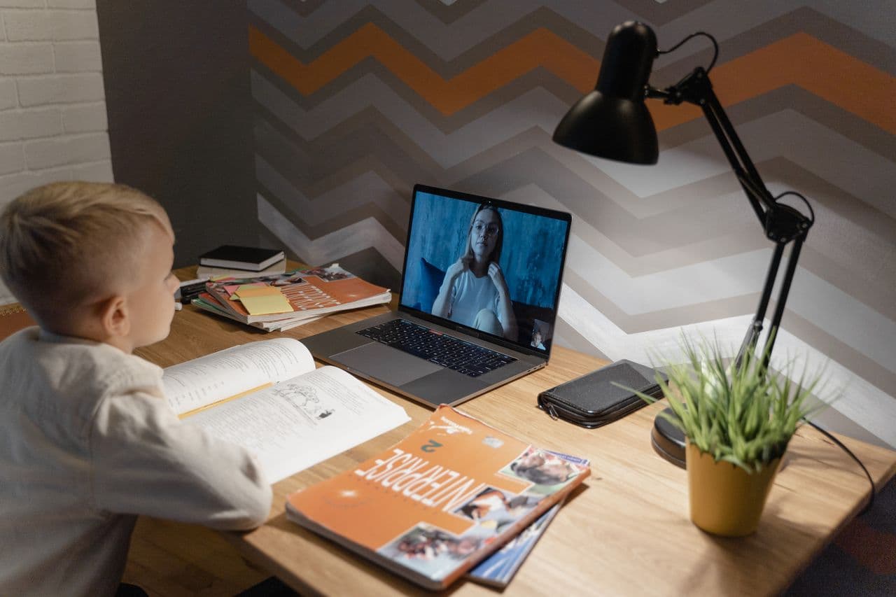 A student learning online with a laptop and notebook at home