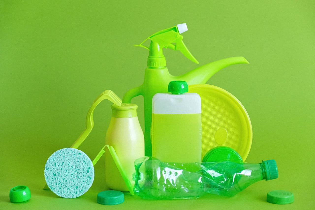Reusable bottle and cloth shopping bag beside plastic bottles and bags